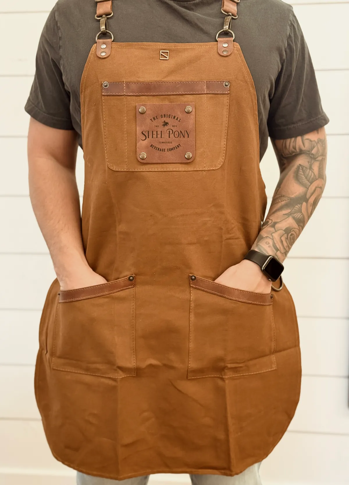 A Steel Pony team member wearing the branded waxed-canvas apron with the leather Steel Pony patch