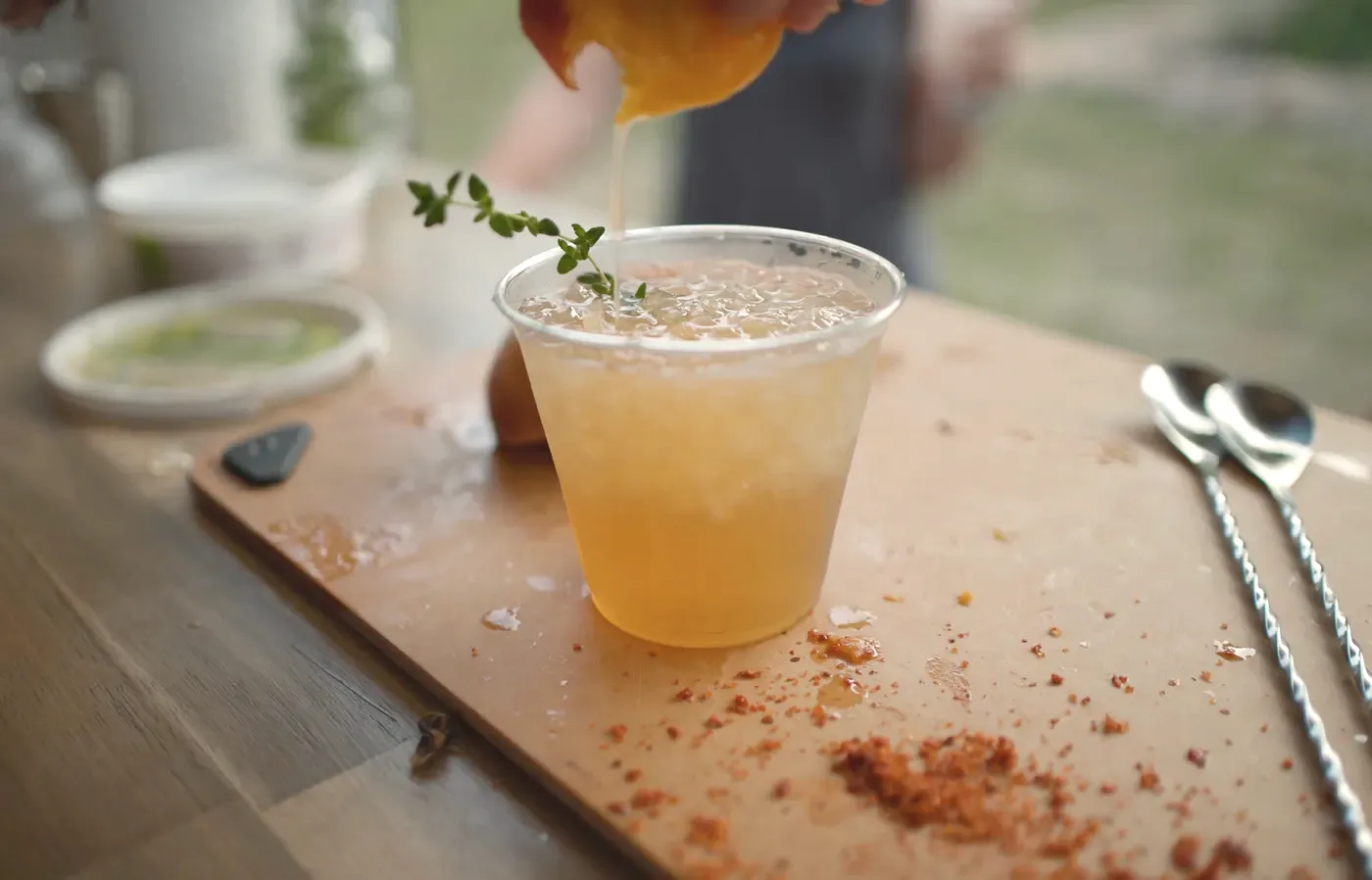 A craft cocktail garnished and served on a wood board